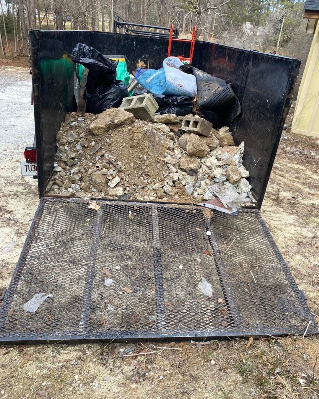 A dumpster filled with rocks and trash is sitting on the ground.