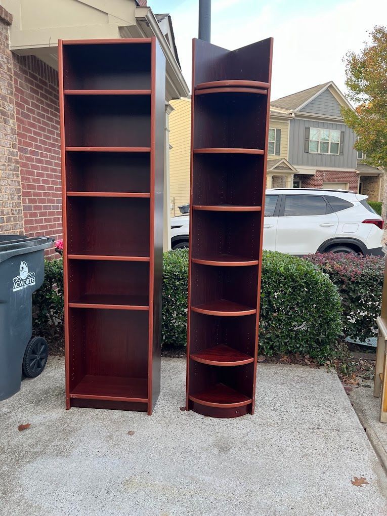 Two wooden shelves are sitting next to each other on a sidewalk in front of a house.