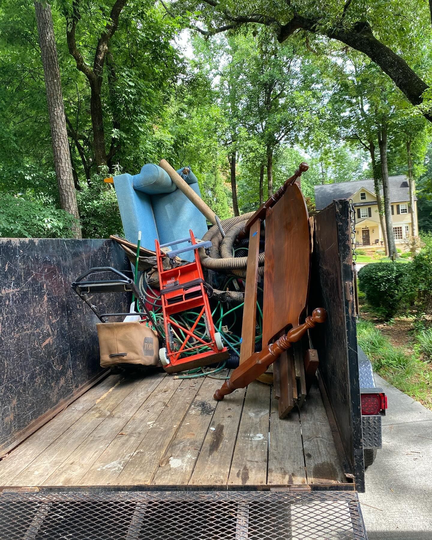 A dumpster filled with junk is parked in front of a house.