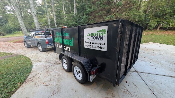 A dumpster trailer is parked in a driveway next to a truck.