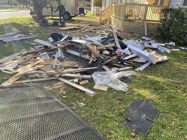 A pile of wood is sitting in the grass in front of a house.