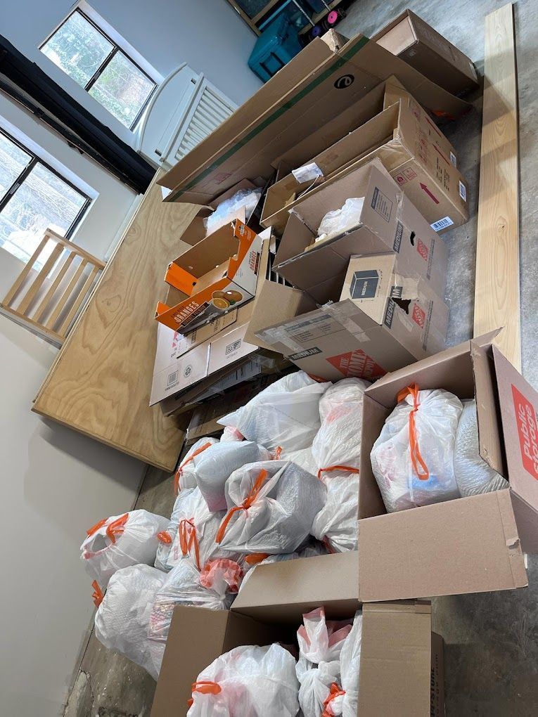 A pile of cardboard boxes and plastic bags on the floor.