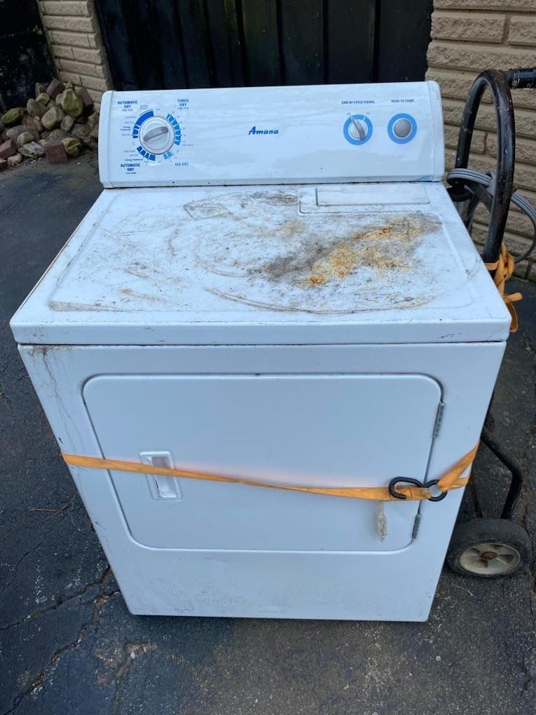 A white washing machine and dryer are tied together with a yellow strap.