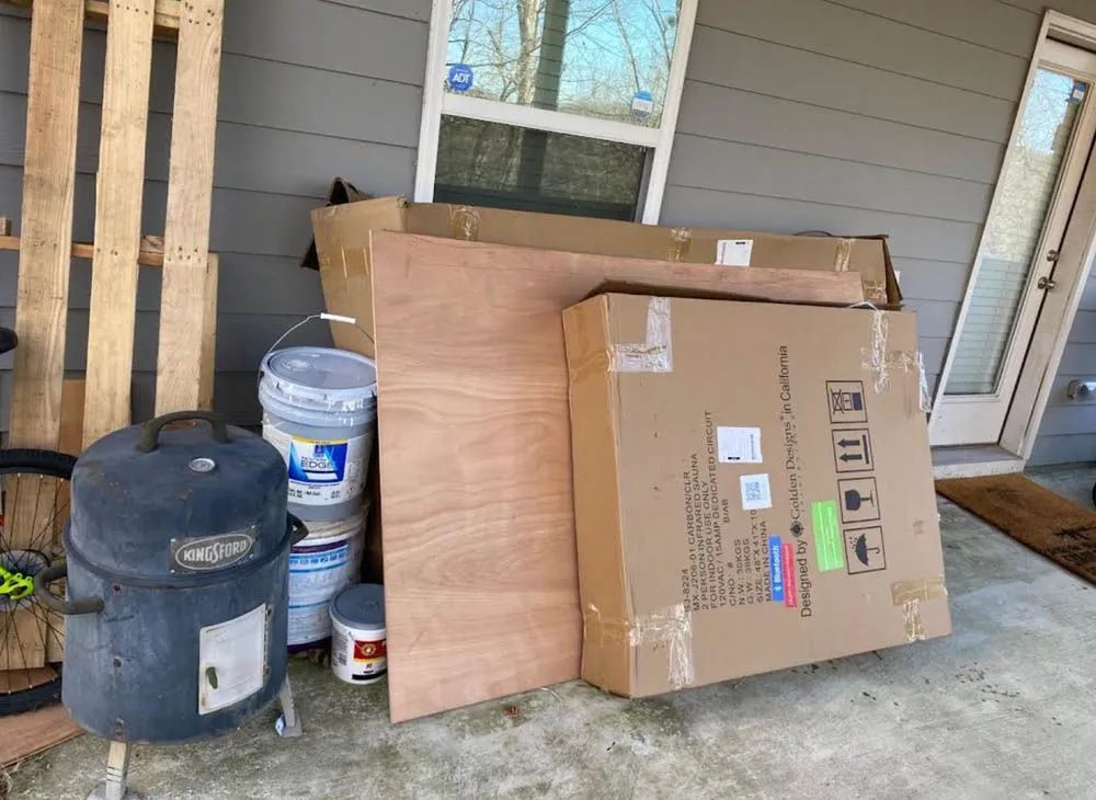A large cardboard box is sitting on the sidewalk in front of a house.