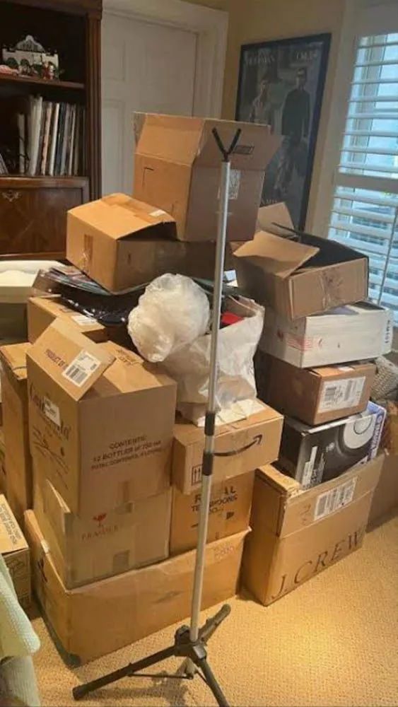 A pile of cardboard boxes are stacked on top of each other in a living room.
