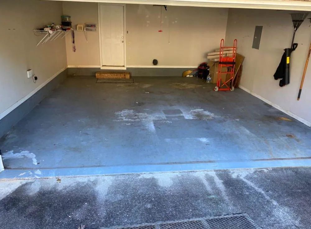An empty garage with a blue floor and a door.