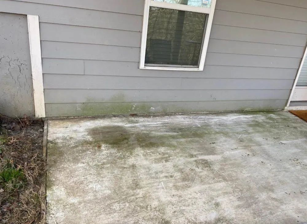 A concrete patio in front of a house with a window.