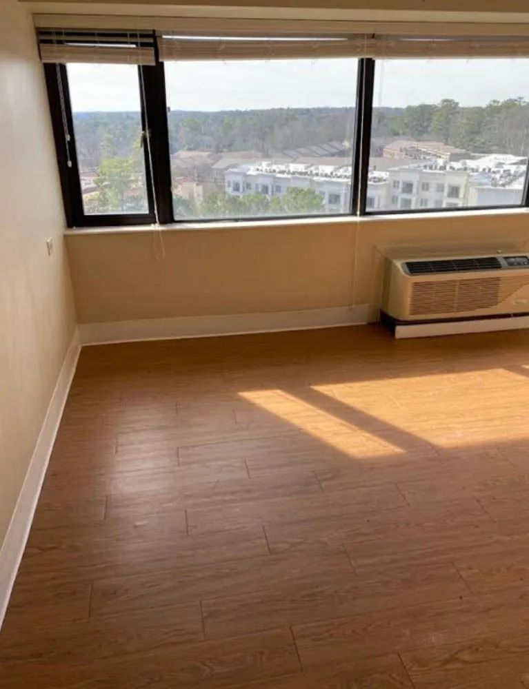 An empty room with hardwood floors and a large window.