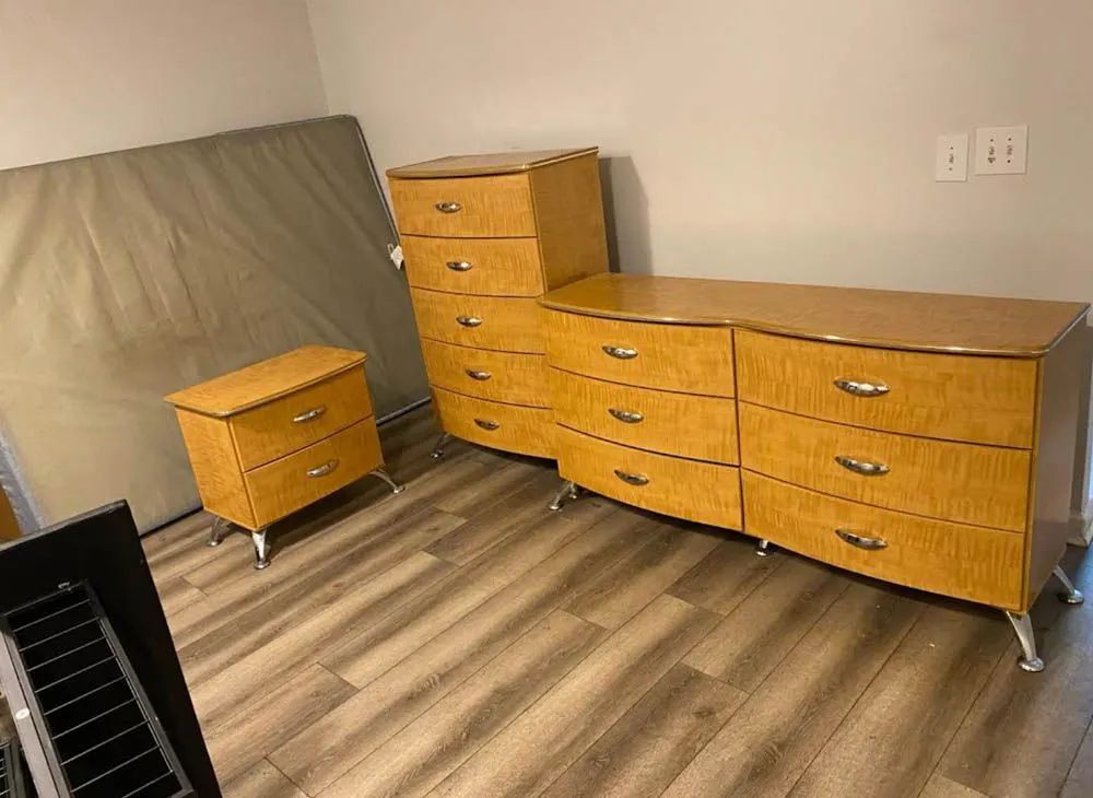 A bedroom with a dresser , nightstand , and mattress.