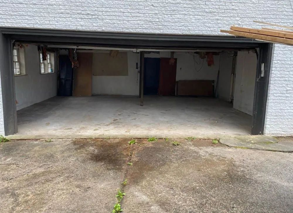 An empty garage with a brick wall and a concrete floor.