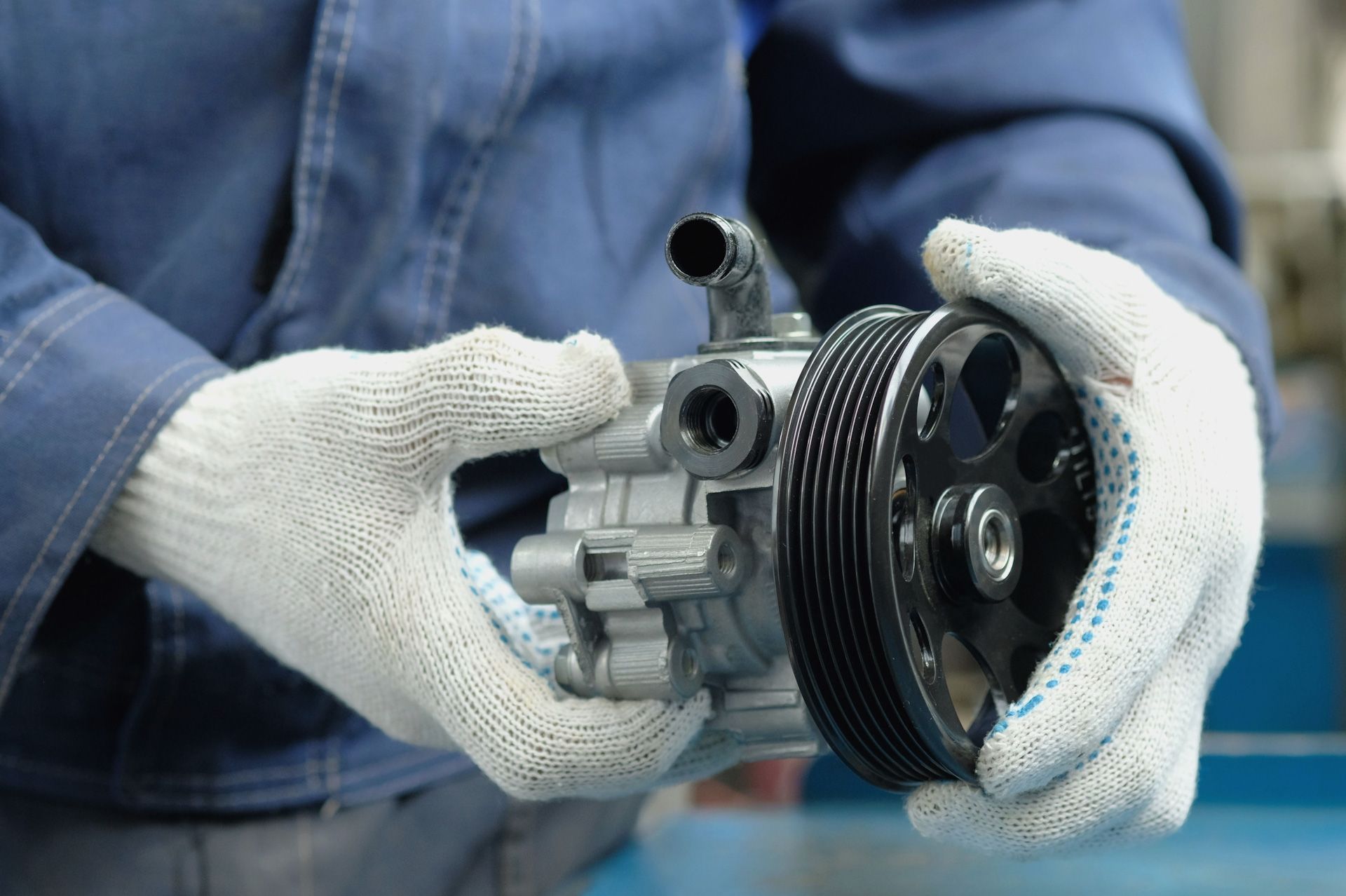 A man is holding a power steering pump in his hands.
