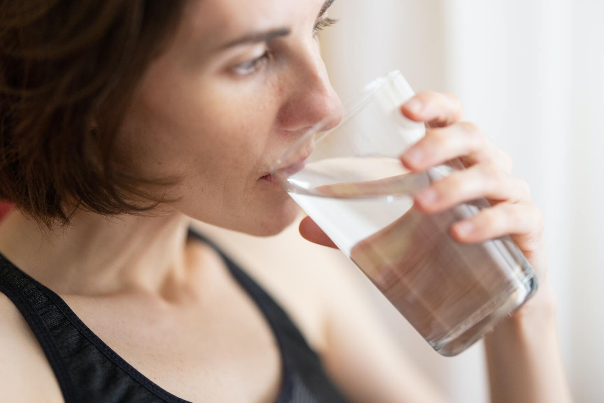 mujer bebiendo agua potable en vaso de vidrio