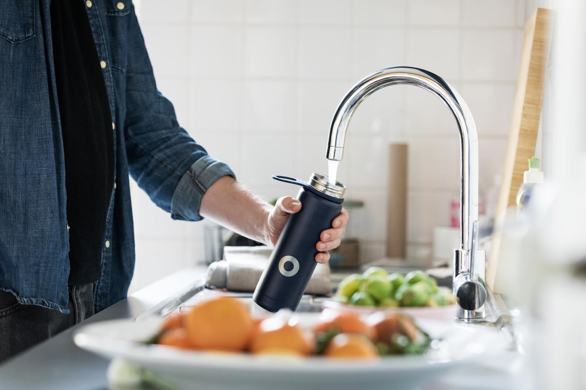 Persona llenado un termo con agua para beber del grifo