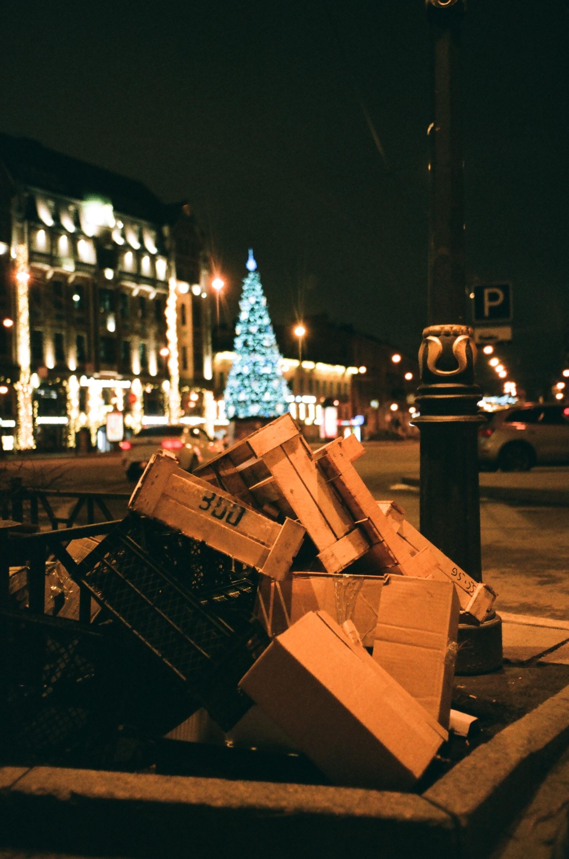 cajas de basura tiradas en la calle frente a un árbol de navidad