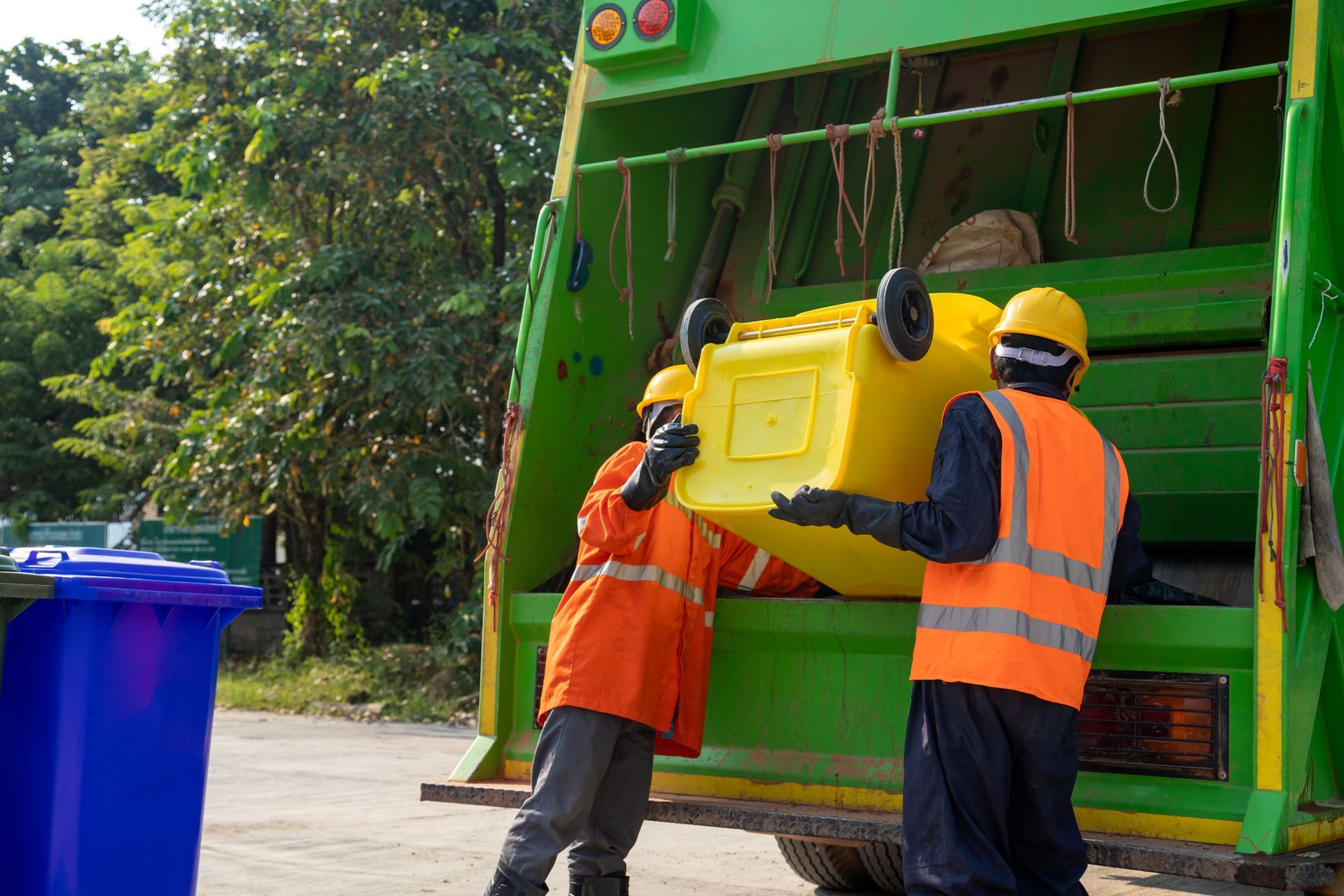 hombres metiendo los desechos del contendor al camión de basura 