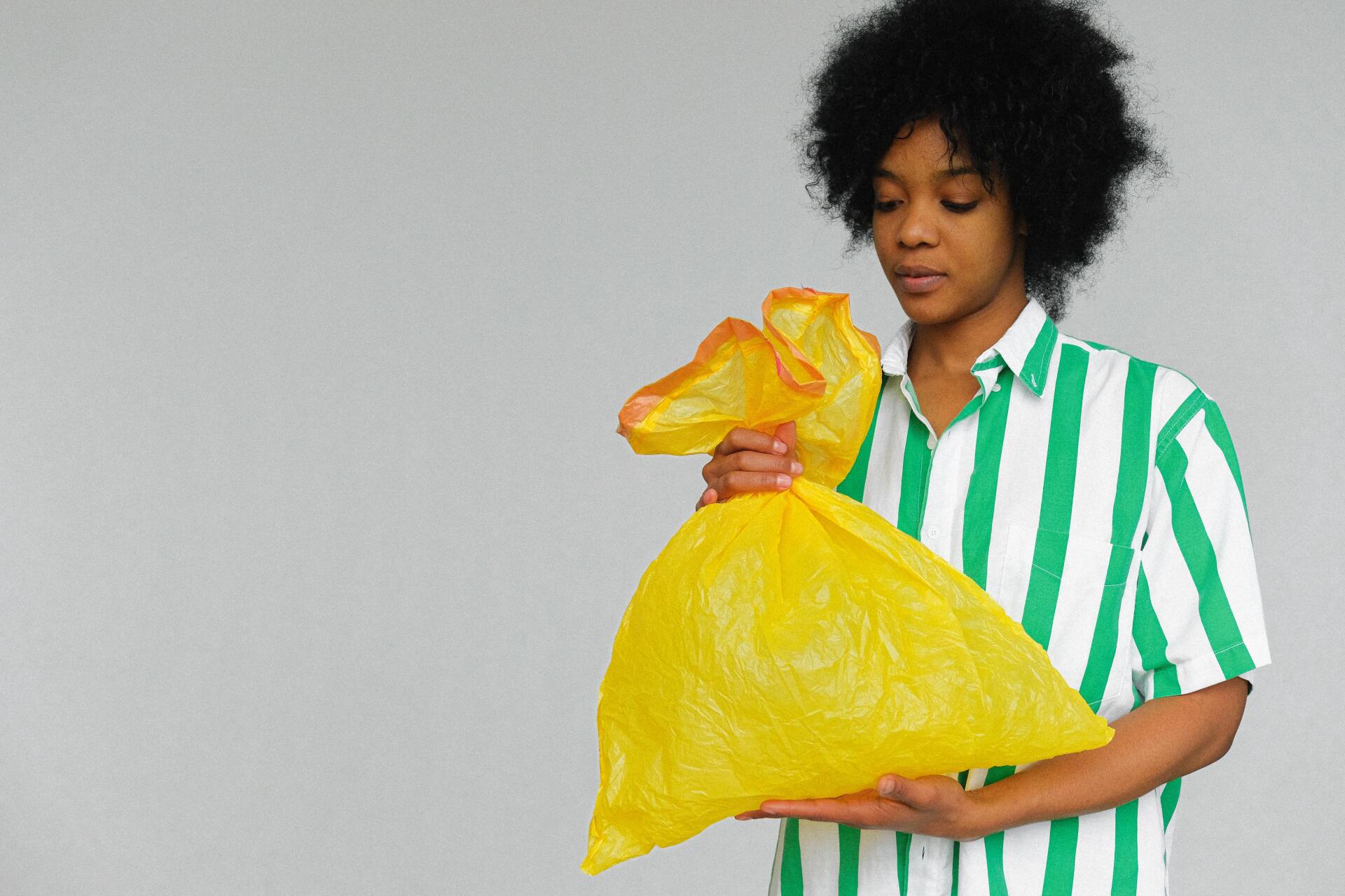 mujer sosteniendo bolsa de basura amarilla