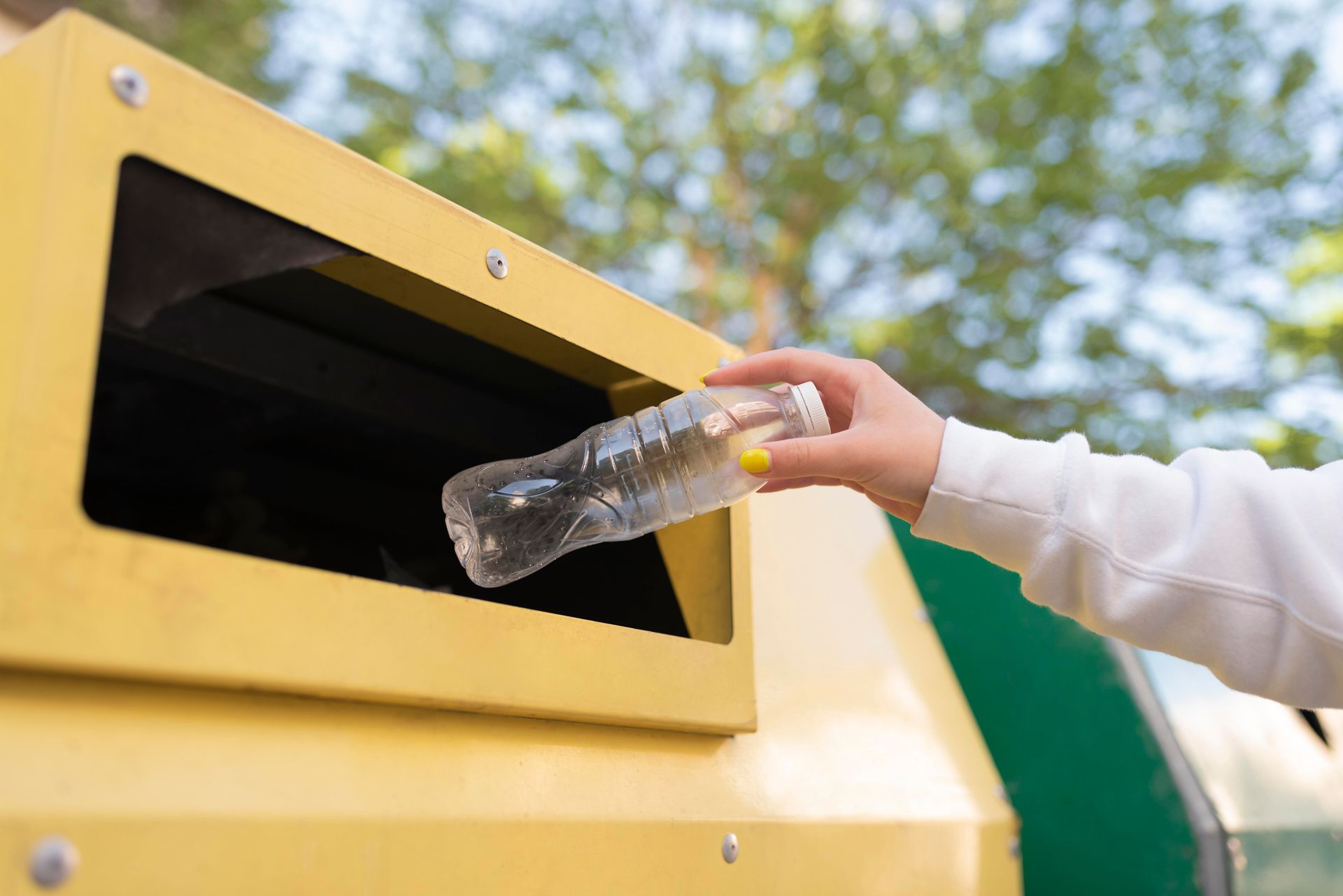 Mujer tirando una botella en un servicio de recolección de basura sostenible