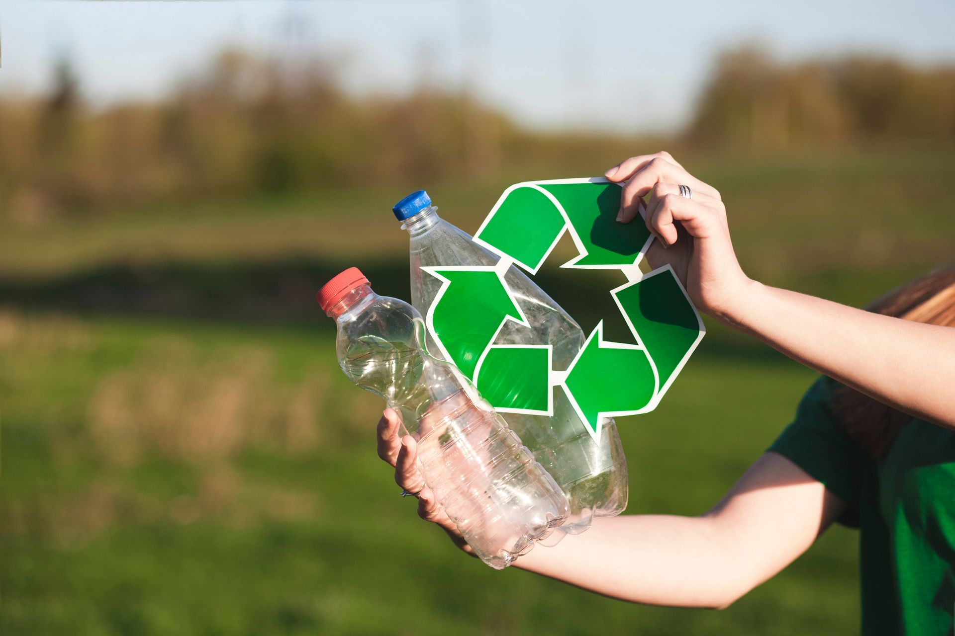mujer con botella de pet en manos con símbolo de reciclaje 