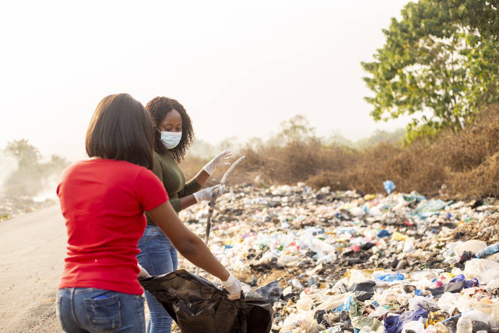 Dos jóvenes adolescentes hermosos con mascarilla y empacando tierra para reciclar