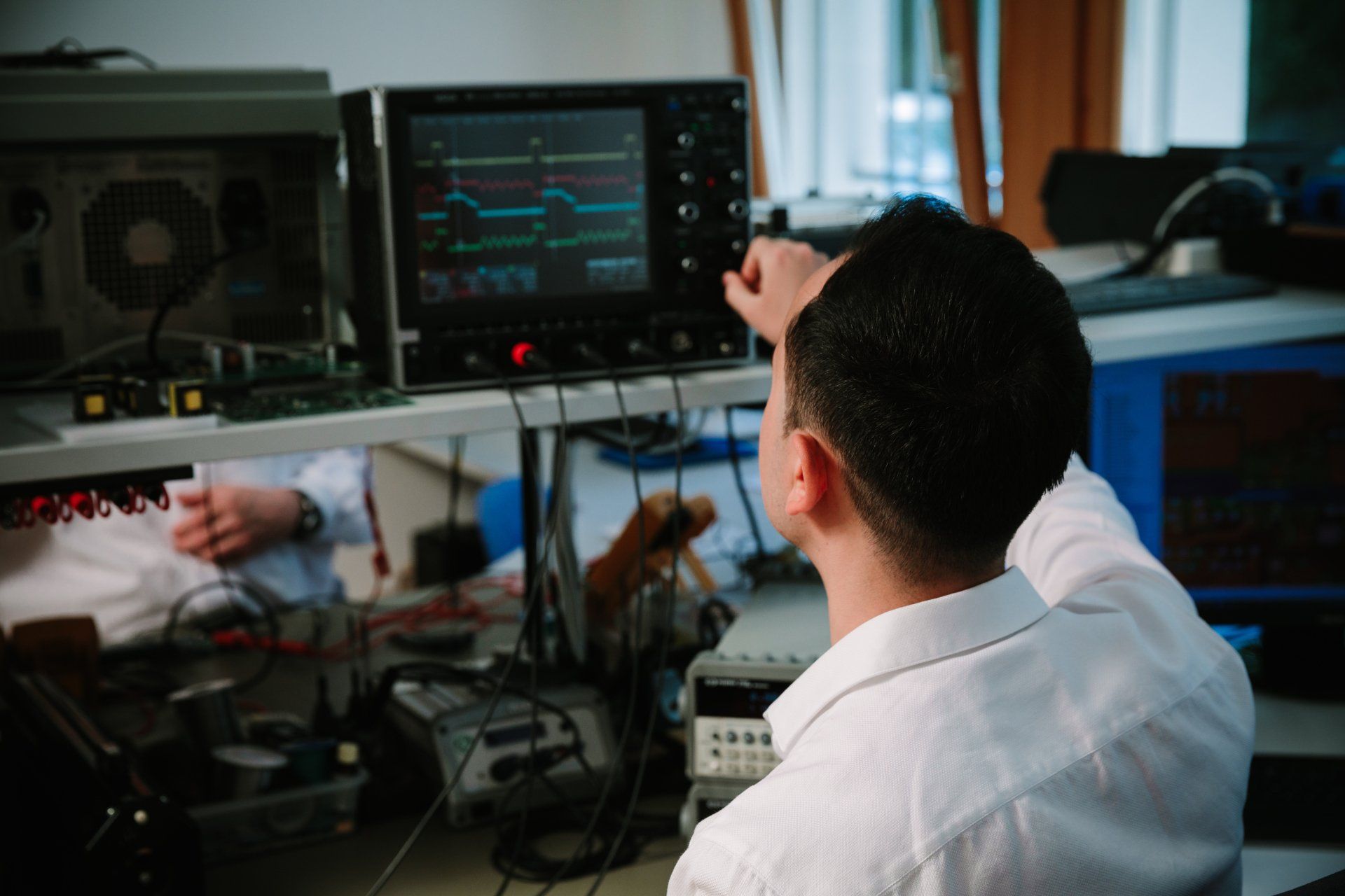 A man is sitting in front of a monitor in a lab.