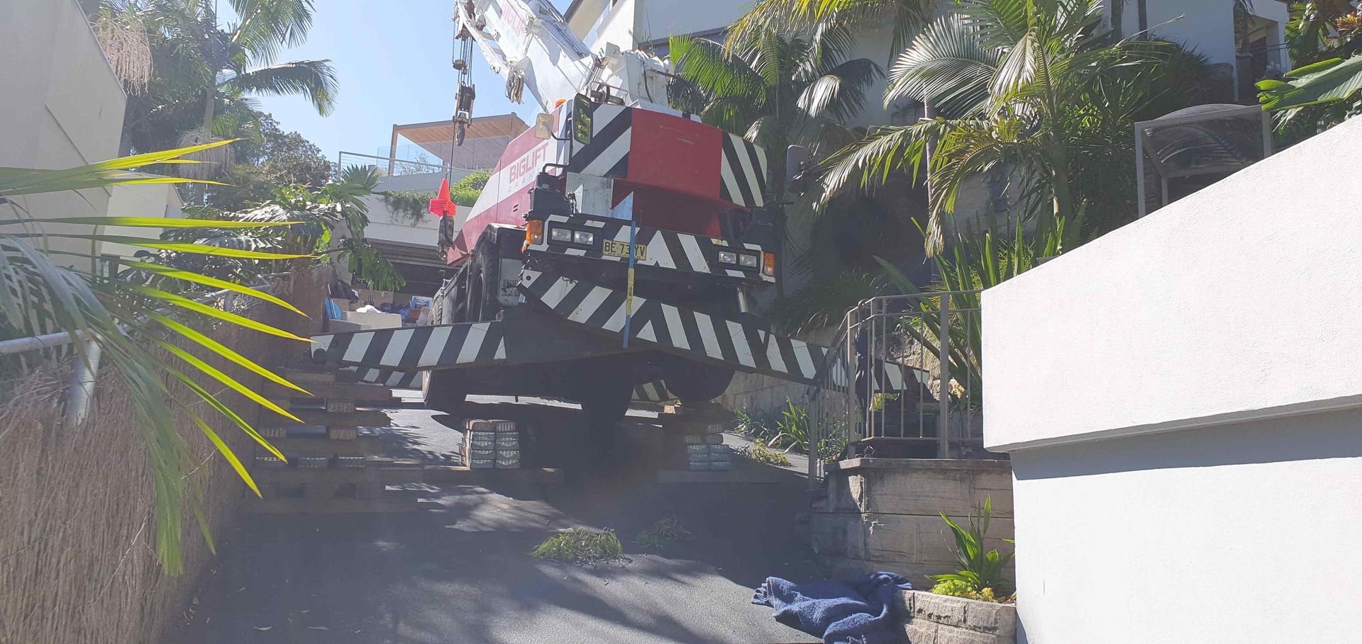 A large truck is driving down a street next to a house.