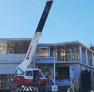 A large crane is sitting in front of a building under construction.