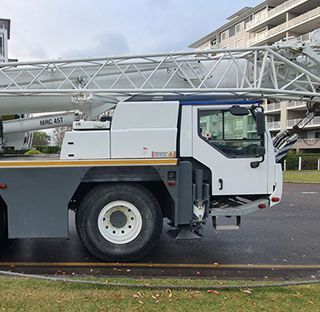 A large white truck with a crane on the back is parked on the side of the road