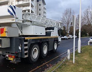 A large white truck with a crane on the back is parked on the side of the road.