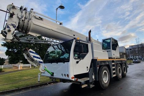 A large white crane truck is parked on the side of the road.