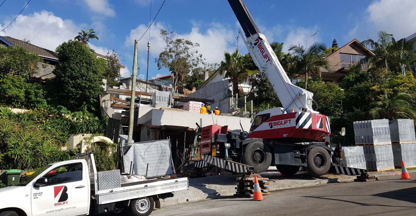 A white truck is parked in front of a crane on a construction site.