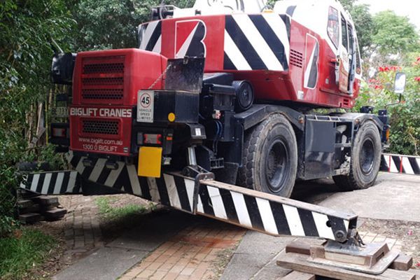 A red and black crane is parked on the side of the road