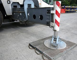 A crane is sitting on a concrete platform in a parking lot