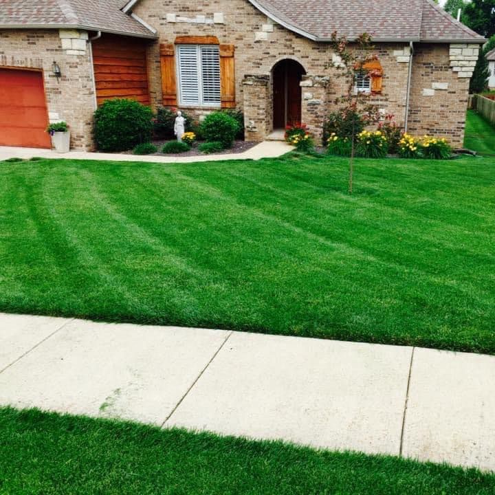 A brick house with a lush green lawn in front of it
