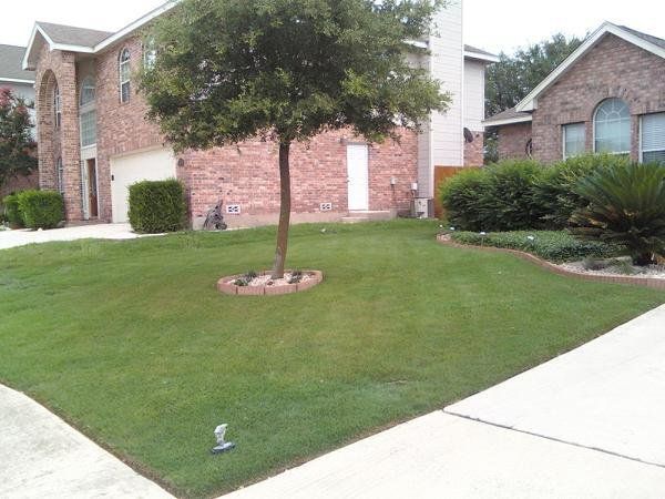 A brick house with a lush green lawn in front of it