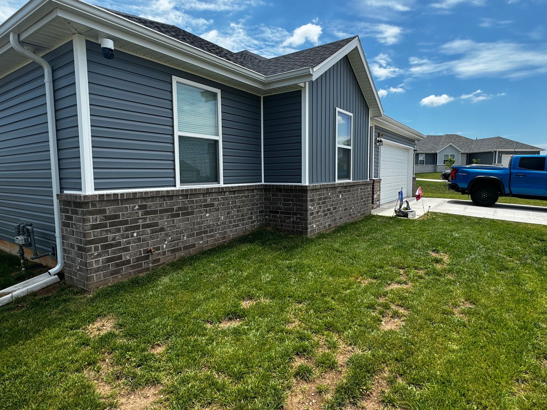 A blue truck is parked in front of a house