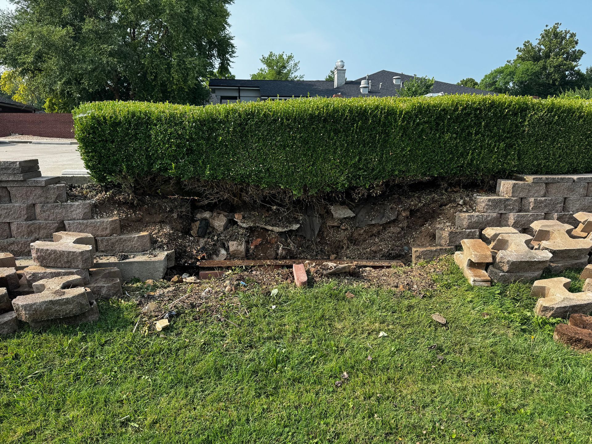 A stone wall with a hedge in the background