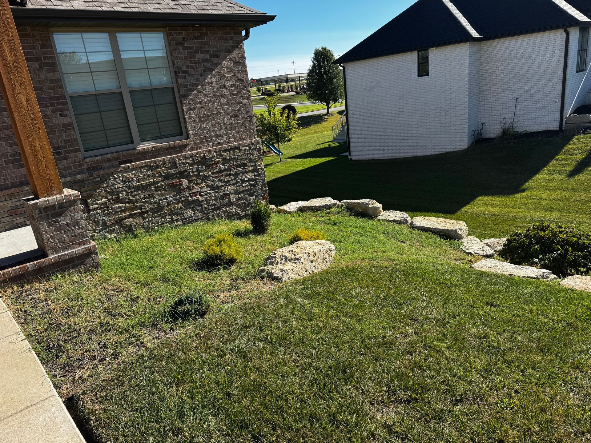 A white house with a black roof sits next to a brick house