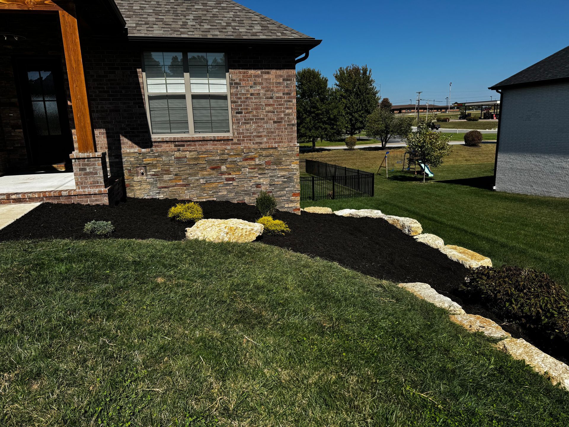 A brick house with a lush green lawn in front of it