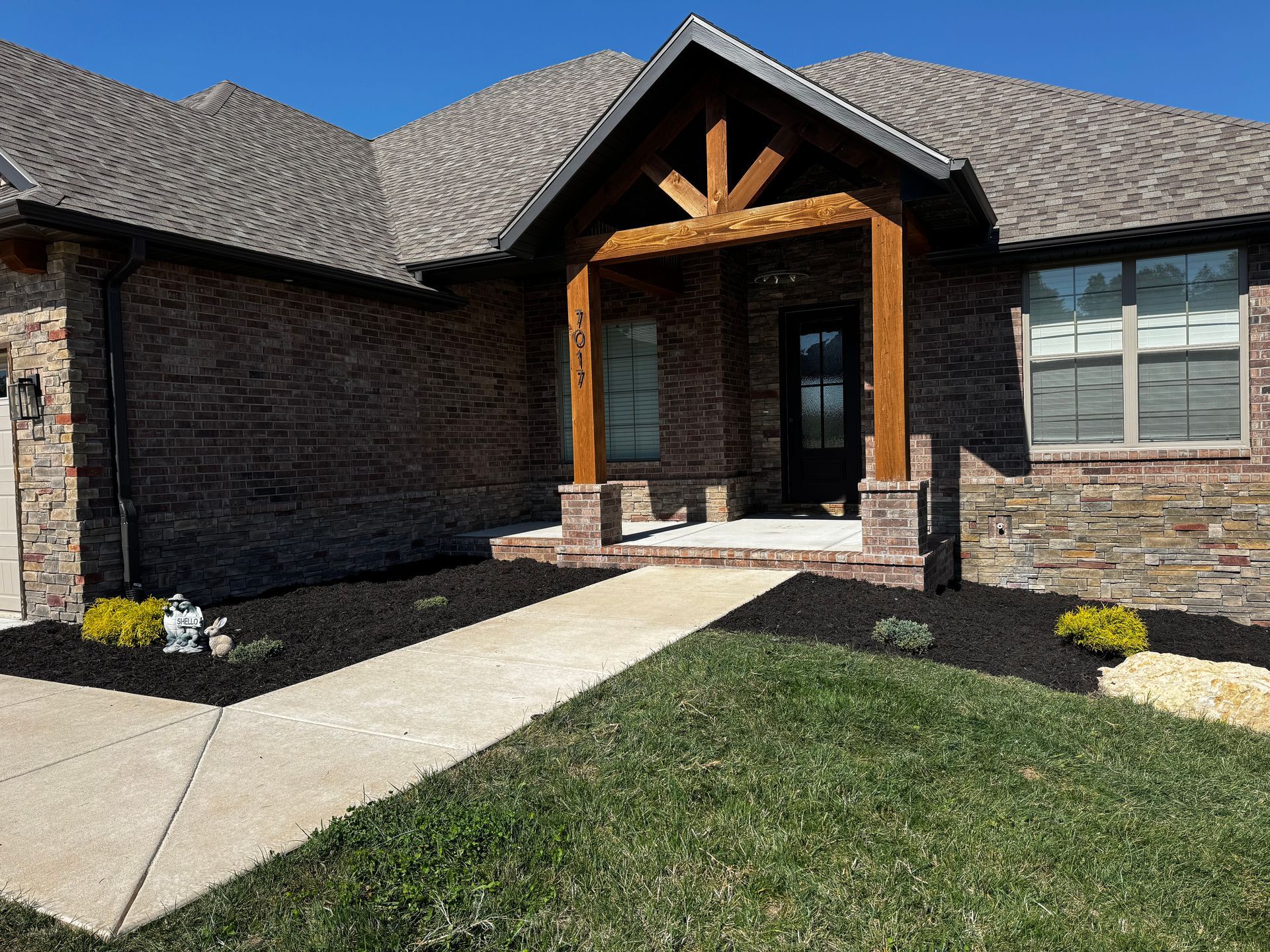 A brick house with a gray roof and a wooden porch
