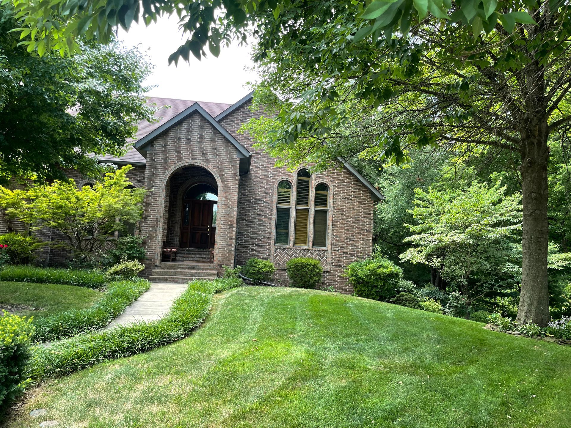 A brick house with a lush green lawn in front of it