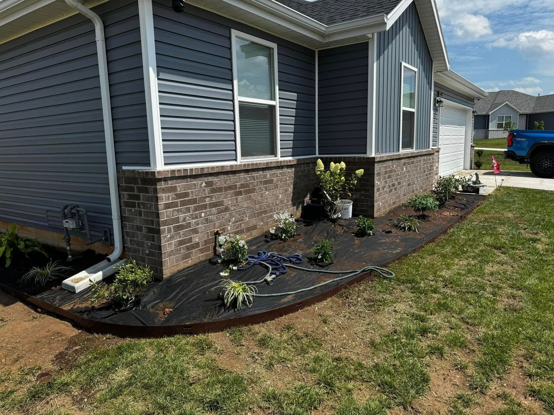 A blue truck is parked in front of a house.