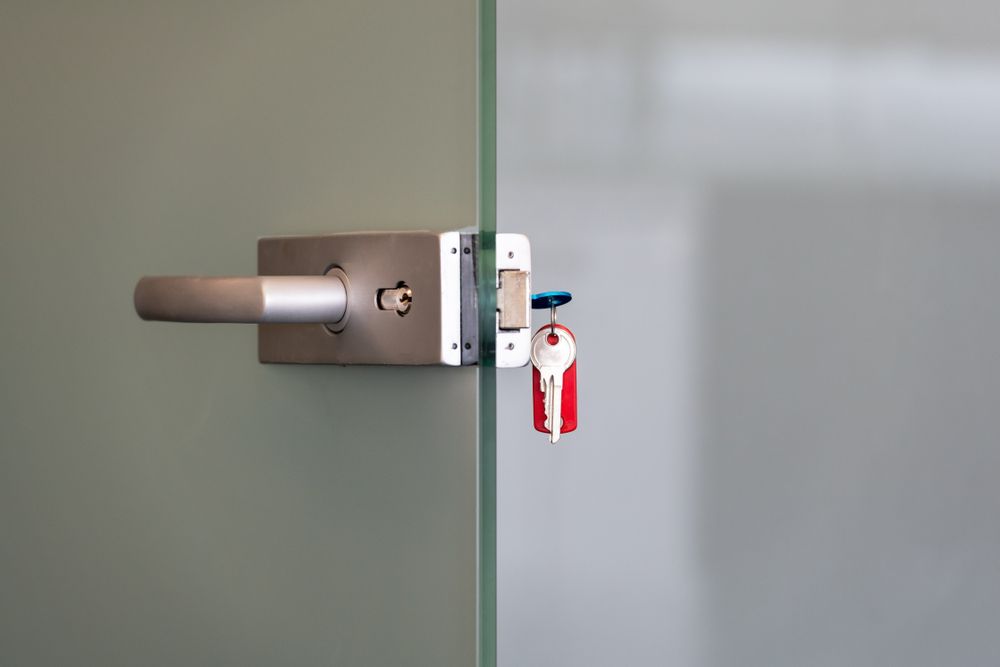 Silver Door Handle and Lock on a Glass Door; Keys Hanging in the Lock — North East Locksmiths in Wodonga, VIC