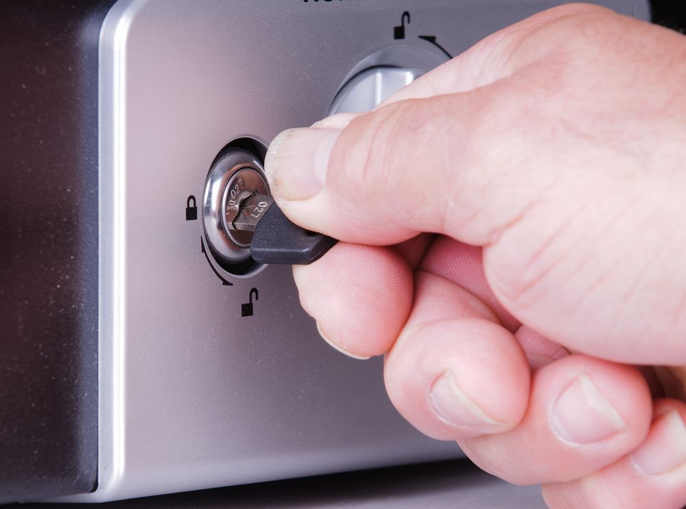 Hand With a Key Turning a Lock on a Metallic Control Panel — North East Locksmiths in Corowa, NSW