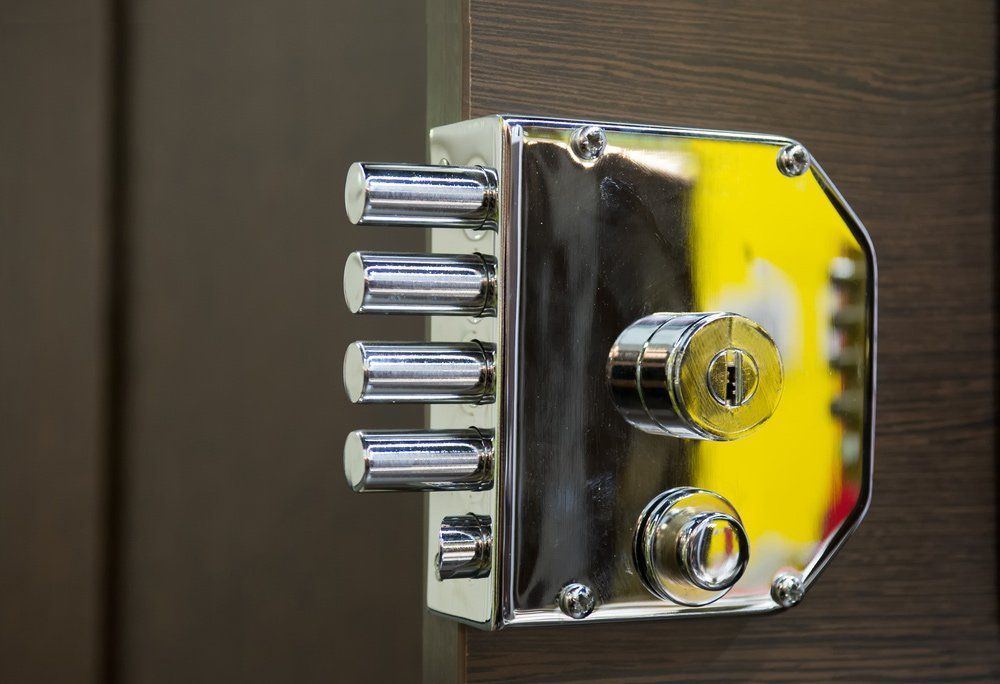 Close-Up of a Shiny Chrome Door Lock With Multiple Bolts, Mounted on a Brown Wooden Door — North East Locksmiths in Wodonga, VIC