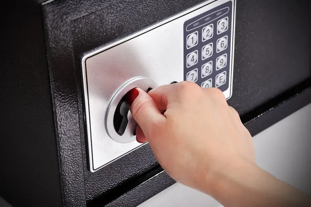 A Hand Turning the Dial on a Black Safe With a Digital Keypad — North East Locksmiths in Wodonga, VIC