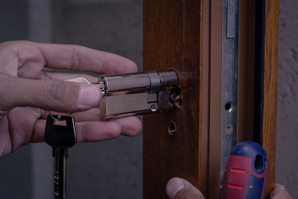 Person Installing a Door Lock Cylinder With a Key and Screwdriver — North East Locksmiths in Wodonga, VIC