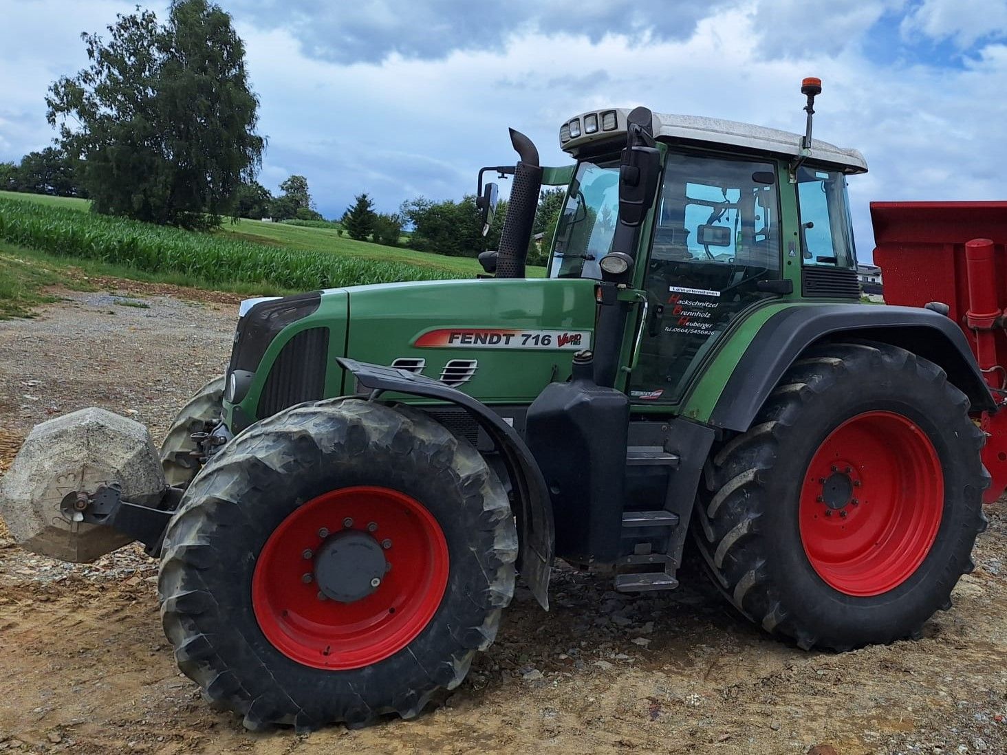 Grüner und roter Fendt-Traktor, der im Freien auf unbefestigtem Boden geparkt ist.
