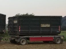 Schwarzer rechteckiger Anhänger auf einem roten Rahmen, auf einem Feld geparkt.