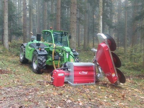 Grüner Traktor mit rotem Forstmulcher in einer Waldlandschaft.
