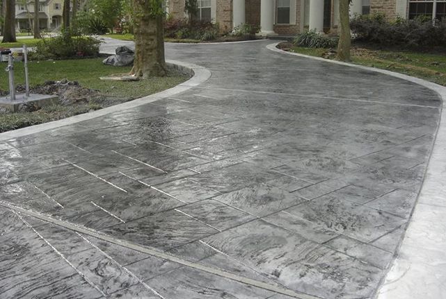 Wet stone driveway curving past a landscaped building entrance